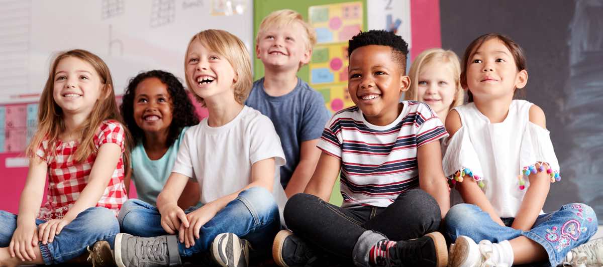 Group Of Elementary School Pupils Sitting On Floor In Classroom